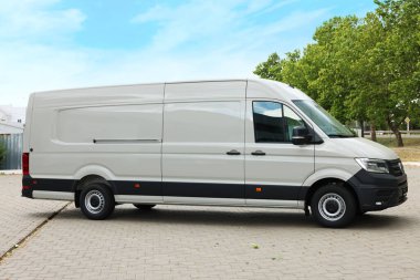 Asfalt yolda park etmiş beyaz bir minibüs.