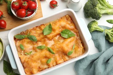 Lezzetli vejetaryen lazanyası fırın tabağında ve malzemeler beyaz masada, düz yerde.