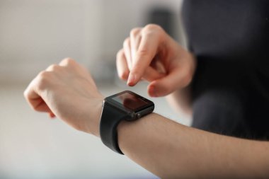 Kadın spor salonunda spor yaparken takip cihazını kontrol ediyor, yakın plan.