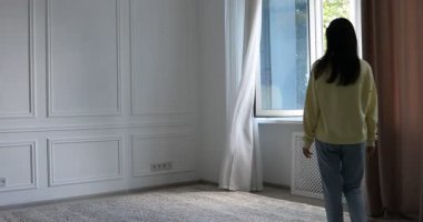 Uyum. Bir kadın evdeki açık pencerenin yanında geriniyor.