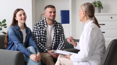 Tüp bebek (tüp bebek). Mutlu çift, üreme kliniğindeki doktorla randevusu sırasında sarılıyor.