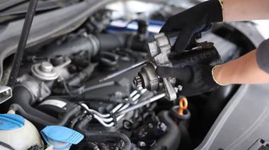 Otomobil parçası. Kaputu açık kaputun yanında motoru olan profesyonel bir tamirci, yakın plan.