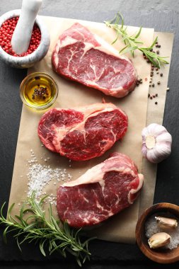Çiğ et parçaları ve baharatlar siyah masanın üzerinde, düz yatıyordu.