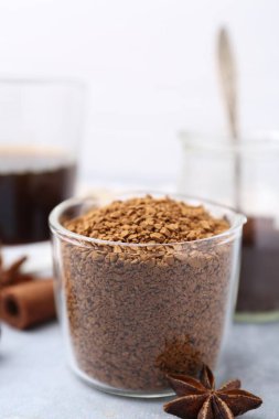 Granüle edilmiş hazır kahve ölçü kabı ve baharatlar gri masa üzerinde hafif arka plan, yakın çekim