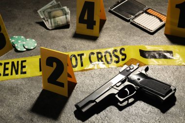 Adli tıp uzmanlığı. Gri arka planda delil, işaret ve polis bandı olan olay yeri, yakın plan.