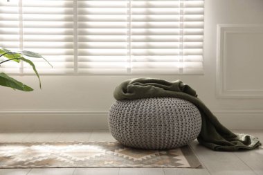 Evde ekose örülmüş şık bir pouf. Metin için boşluk