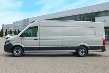 Asfalt yolda park etmiş beyaz bir minibüs.