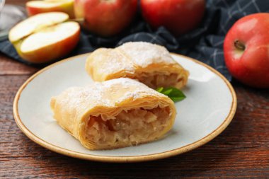 Lezzetli elmalı turta parçaları pudra şekeri, nane ve ahşap masada meyveler, yakın plan.