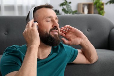 Uyum. Evde kulaklıkla müzik dinleyen bir adam.