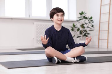 Kapalı alanda yoga yapan mutlu çocuk.