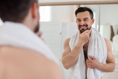 Banyoda aynaya bakarken tıraş olmadan önce gülümseyen adam.