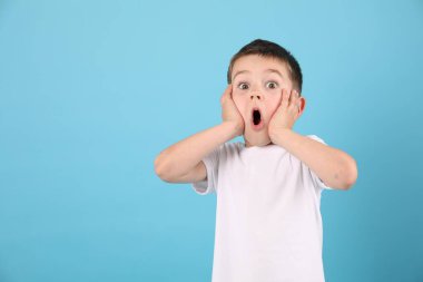 Açık mavi arkaplanda şaşırmış bir çocuğun portresi, metin için boşluk