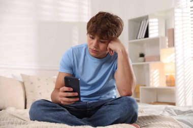 Ergen çocuk evde akıllı telefon kullanıyor.