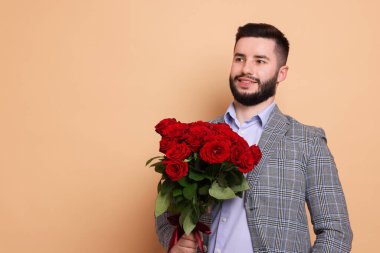 Bej arka planda kırmızı gül buketi olan mutlu adam, metin için boşluk.