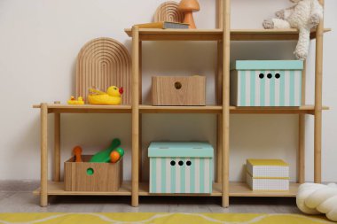 Süslü oyun odasındaki beyaz duvarın yanında dekorlu ve oyuncaklı raf ünitesi. İç tasarım