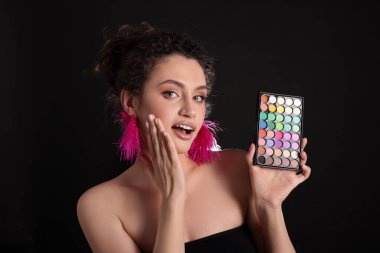 Siyah arka planda parlak göz falı olan şaşırmış bir kadın.