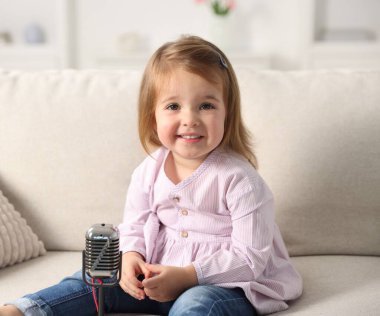 Evdeki kanepede mikrofonlu şirin küçük kız.