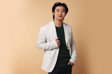 Bej arka planda takım elbiseli yakışıklı Asyalı işadamının portresi