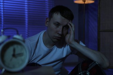 Evde yerde uykusuzluk çeken sinirli bir adam.