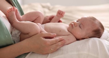 Anne yeni doğmuş bebeğini evde yatırıyor, yakın plan.