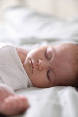 Sevimli yeni doğmuş bebek yatakta uyuyor, yakın plan.