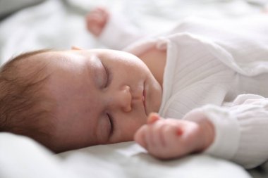 Sevimli yeni doğmuş bebek yatakta uyuyor, yakın plan.
