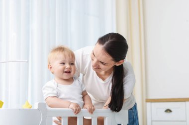 Anne evde beşikte sevimli bebeğiyle oynuyor.