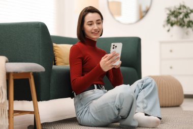 Evde modern akıllı telefon kullanan bir kadın.