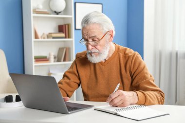 Üst düzey adam içeride masa başında öğrenirken not alıyor. Kendi kendine çalışma.