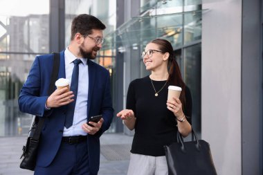 Kahveli mutlu iş arkadaşları ofis binasının yakınında bir şeyler tartışıyorlar.