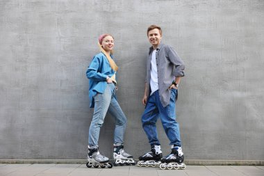 Gri duvarın yanında patenli mutlu çift