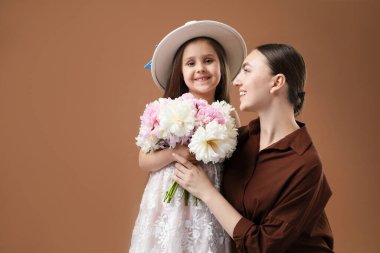 Anne ve kızı kahverengi arka planda bir buket güzel şakayıkla mesajlaşmak için yer açıyorlar.