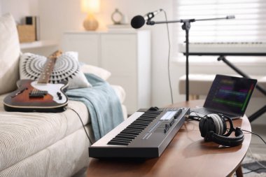 MIDI klavye, dizüstü bilgisayar ve kulaklıklar ev stüdyolarındaki ahşap masada.
