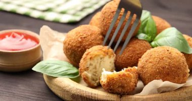 Lezzetli bir kızarmış köfteyi çatalla alıp ahşap masada ketçapa batırmak, yakın plan.