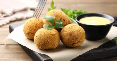 Ahşap masada çatallı, leziz kızarmış köfte topunu alıp, yakın plan.