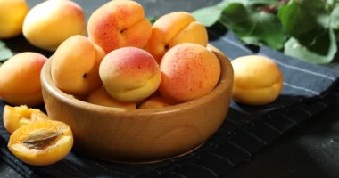 Siyah masanın üstünde taze olgun kayısılar, yakın plan. Kamera sola hareket ediyor