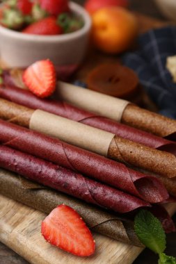 Lezzetli deri rulo şekerler, ahşap masada meyveler, yakın plan.