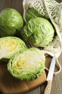 Taze lahanalar, ağ torbası ve bıçak ahşap masada, yakın plan.