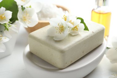 Sabun barı, deniz tuzu, temel yağ ve yasemin çiçekleri beyaz ahşap masada, yakın plan.