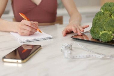 Beyaz mermer masa içinde diyet planı geliştiren kadın, yakın plan.