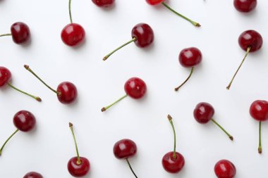 Beyaz arka planda taze kirazlar, düz uzanmış.