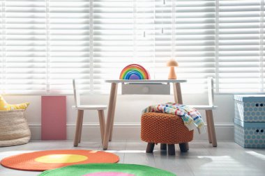 Küçük masa, sandalyeler, puf ve oyuncak şık oyun odasında. İç tasarım