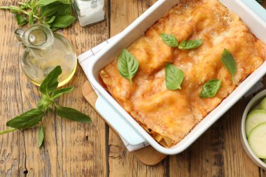 Pişirme kabında leziz vejetaryen lazanya ve ahşap masada malzemeler.