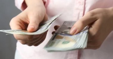 Açık gri arka planda dolar banknotları sayan kadın, yakın plan