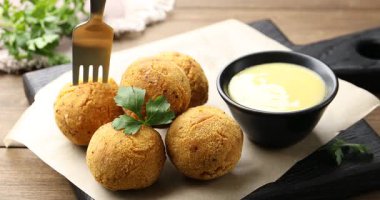 Lezzetli kızarmış köfteyi çatalla alıp ahşap masada sosa batırmak, yakın plan.