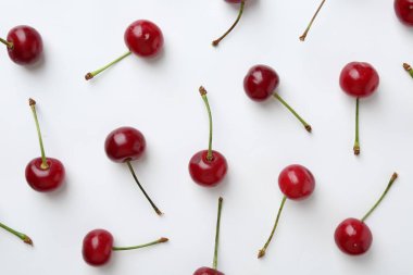 Beyaz arka planda taze kirazlar, düz uzanmış.