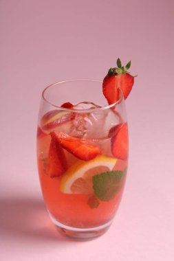 Pembe arka planda çilek, nane, limon ve buzlu içecek, yakın plan.