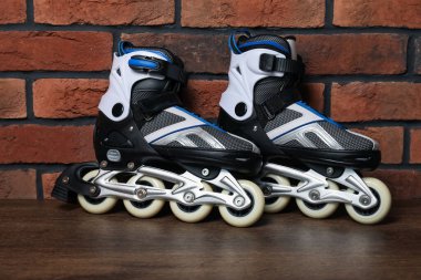 Tuğla duvarın yanındaki ahşap masada bir çift paten.