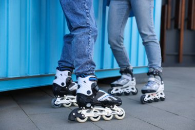 Açık mavi duvarın yanında patenli çift, yakın plan.