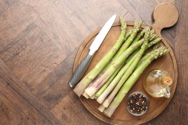 Taze çiğ kuşkonmaz, baharatlar, ahşap masada yağ ve bıçak, üst manzara. Metin için boşluk